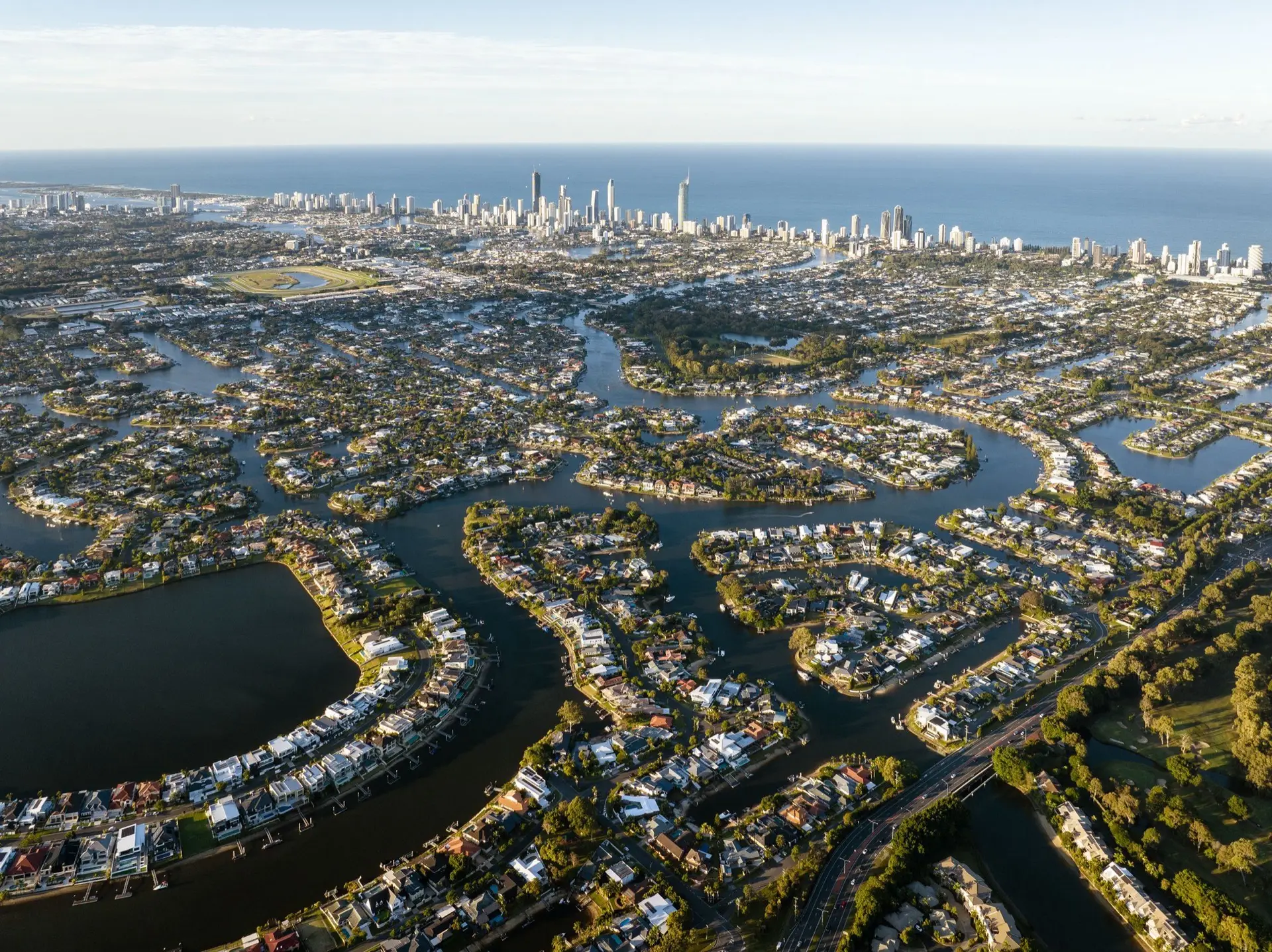 Aerial view of Gold Coast canal homes with backyard pools and the Surfers Paradise skyline