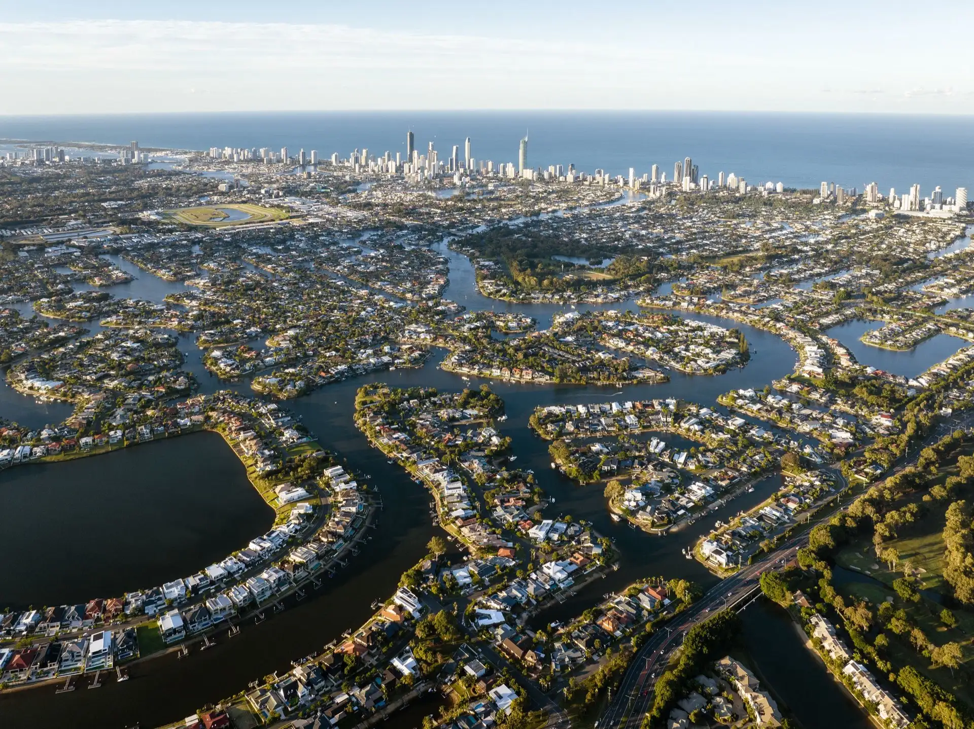 Aerial view of Gold Coast canal homes with backyard pools and the Surfers Paradise skyline