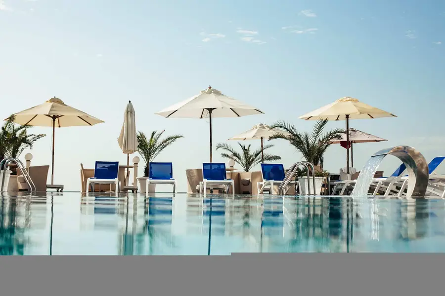 A large shared resort pool surrounded by sun lounges and palms at a Gold Coast apartment complex